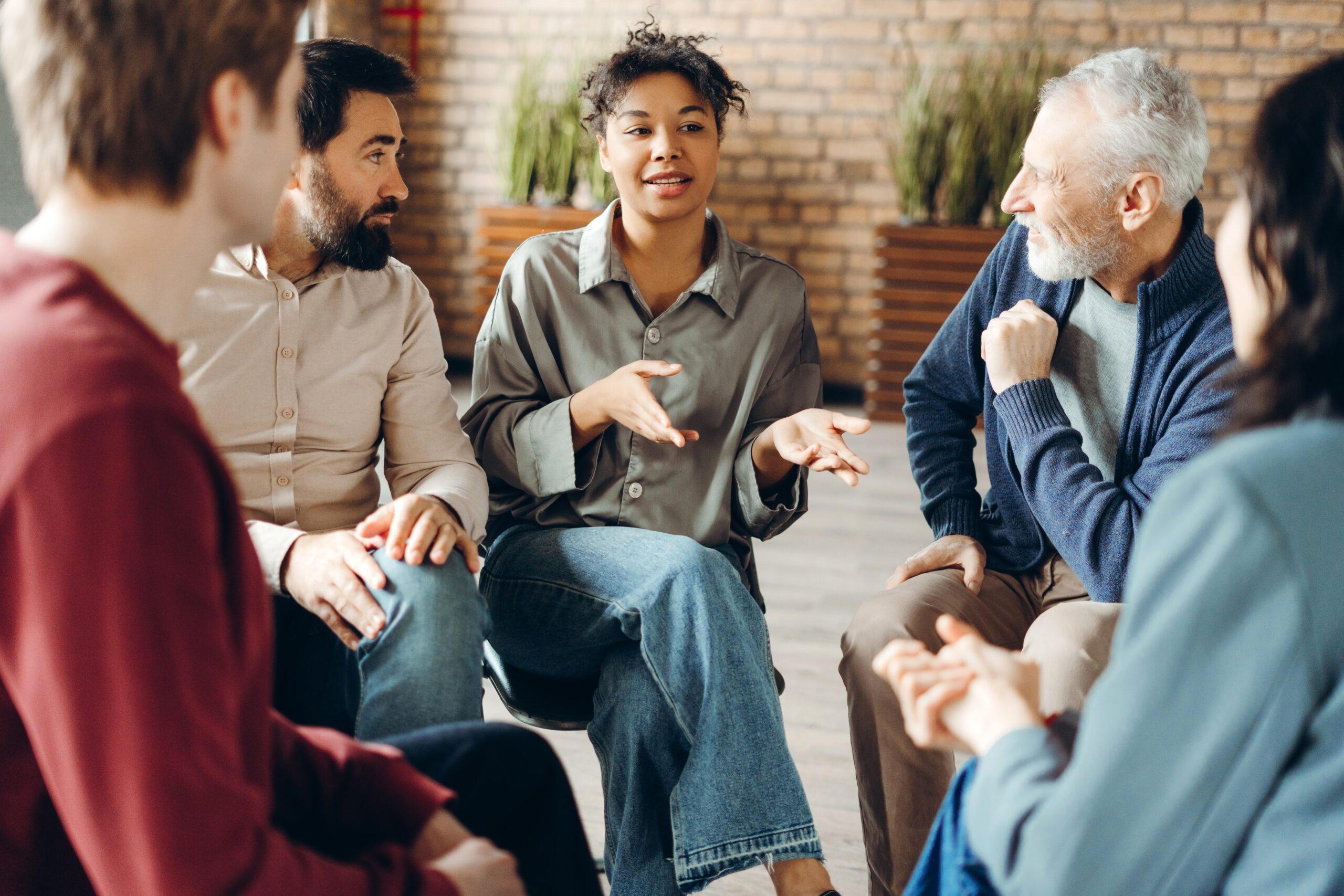 Diverse group of adults sitting in a circle sharing stories and listening during a group discussion